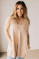 BLONDE WOMAN WEARING AN OVERSIZED V-NECK LONG SOFT SWEATER VEST WITH SIDE POCKETS.