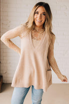 BLONDE WOMAN WEARING AN OVERSIZED V-NECK LONG SOFT SWEATER VEST WITH SIDE POCKETS.