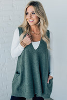 BLONDE WOMAN WEARING AN OVERSIZED V-NECK LONG SOFT SWEATER VEST WITH SIDE POCKETS.