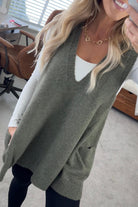 BLONDE WOMAN WEARING AN OVERSIZED V-NECK LONG SOFT SWEATER VEST WITH SIDE POCKETS.