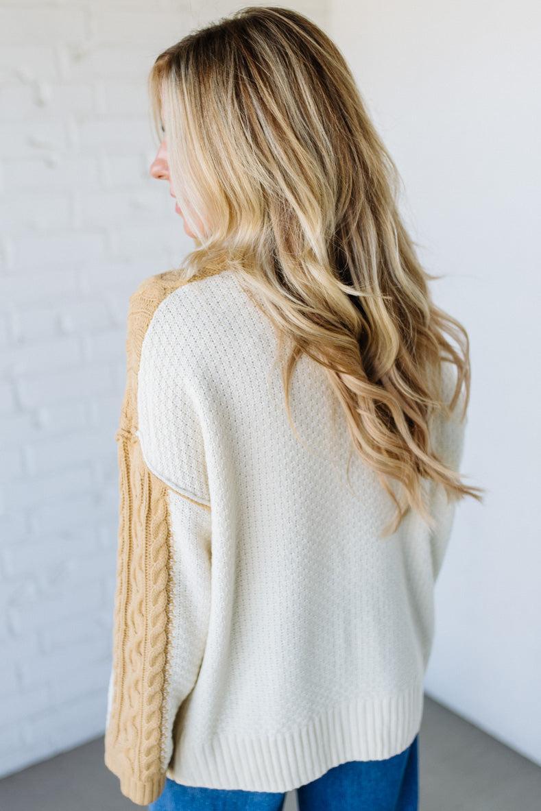 Woman wearing a cream sweater and beige cardigan against a white background