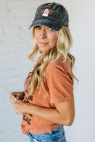 Woman wearing a black cap with 'Spooky' text and an orange shirt against a white background