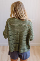 Person wearing a green crochet poncho with a neutral background
