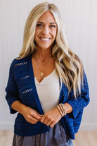 Woman wearing a blue cardigan over a white top with a neutral background