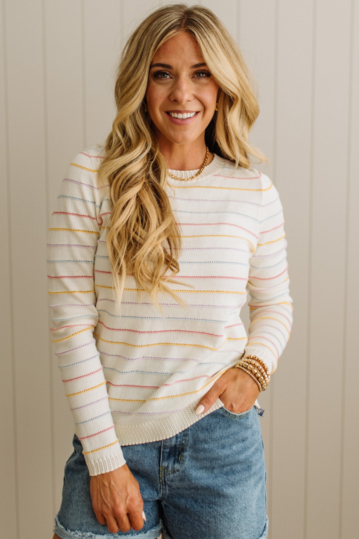 Woman wearing a striped sweater and jeans against a neutral background