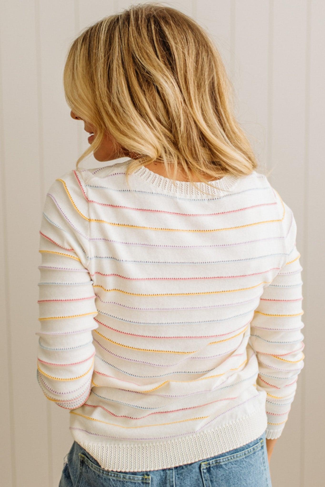 Woman wearing a striped sweater with a neutral background