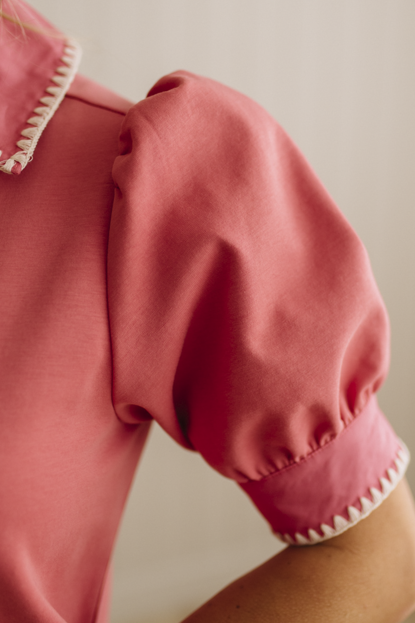 Close-up of a pink garment with white trim on a neutral background