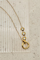 Gold necklace with circular pendants on a textured beige surface