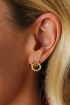 Close-up of a person wearing a gold bow-shaped earring.