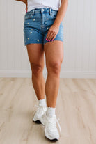 Person wearing blue denim shorts and white sneakers on a light wooden floor.