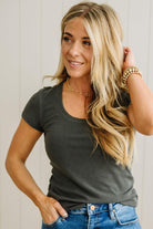 Woman wearing a dark green t-shirt and blue jeans with a neutral background