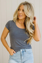Woman wearing a gray t-shirt and light blue jeans against a neutral background
