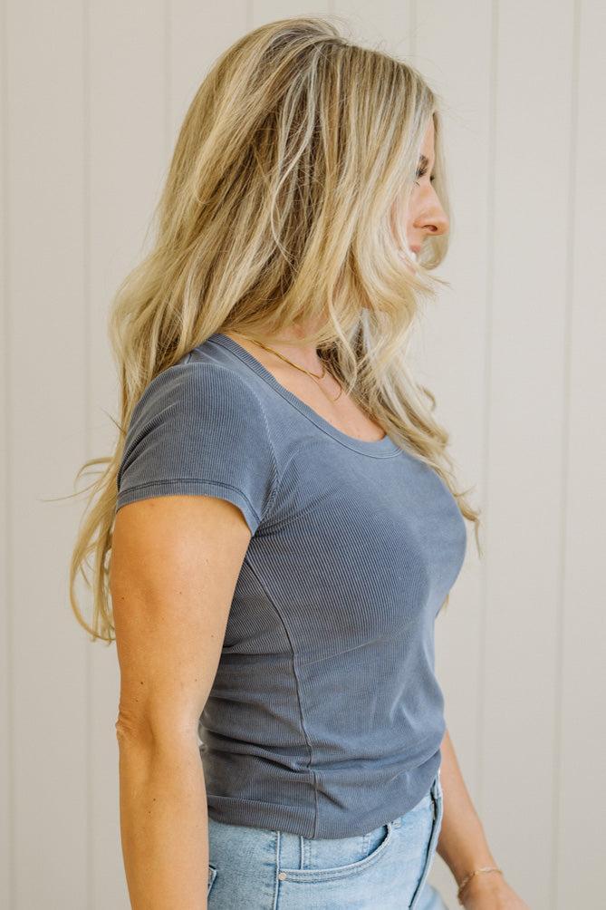 Woman wearing a blue t-shirt and jeans against a neutral background