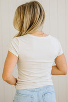 Person wearing a plain white t-shirt and light blue jeans against a neutral background