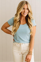 Woman wearing a blue ribbed top and light blue jeans against a neutral background