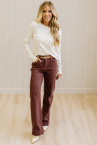 Blonde woman in brown jeans wearing a cream long sleeve tee with brown botanical print.