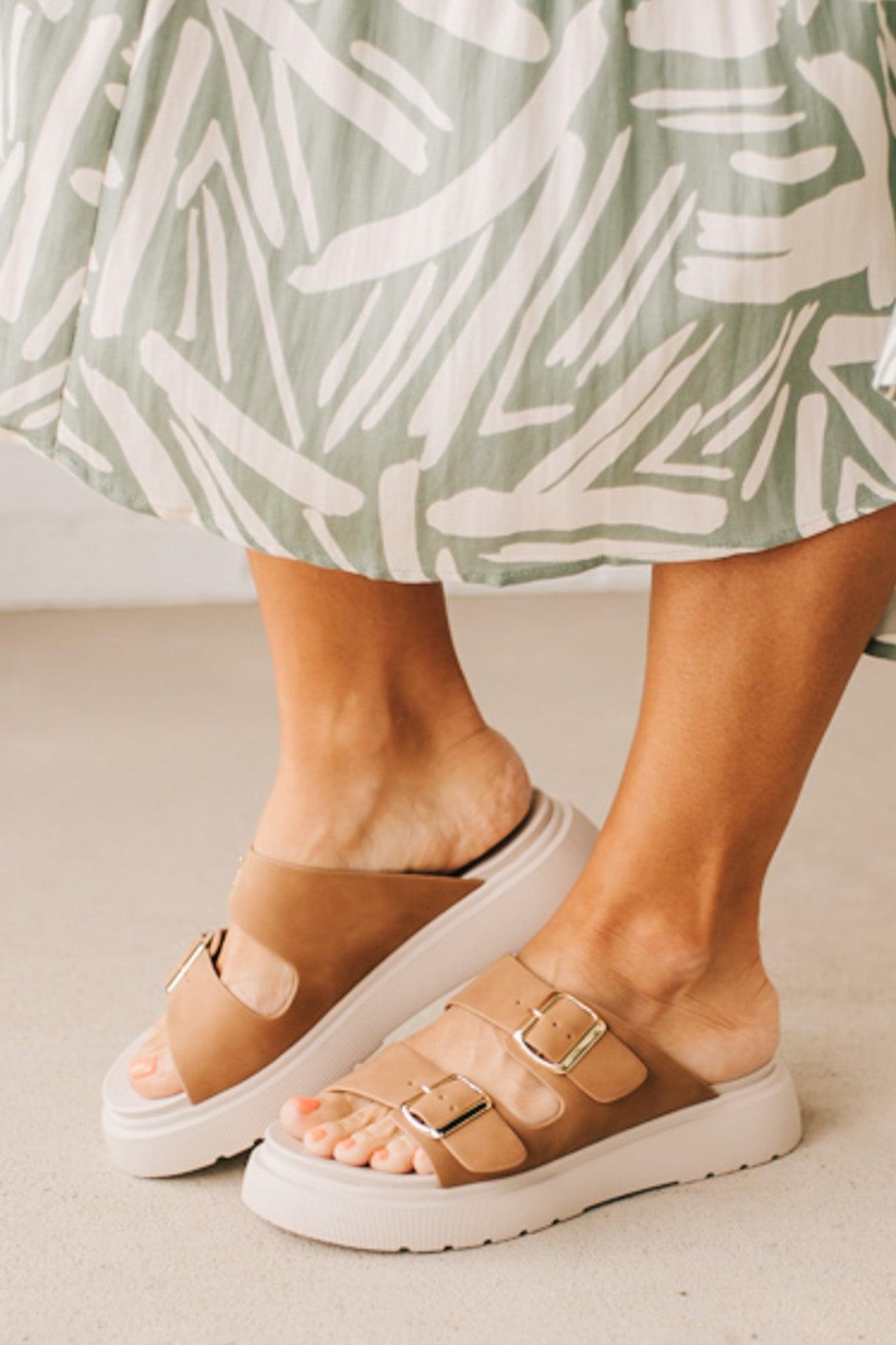 Woman wearing double buckle platform slide sandals with cream sole and cognac vegan leather upper.