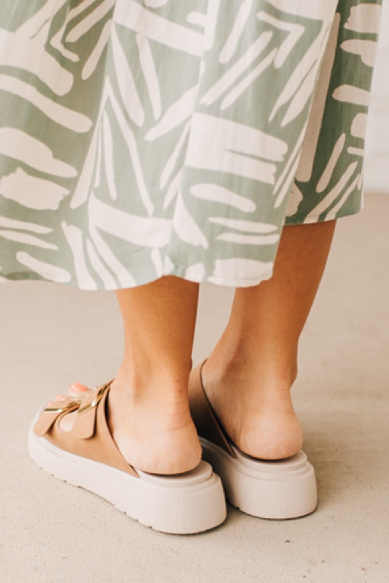 Woman wearing double buckle platform slide sandals with cream sole and cognac vegan leather upper.