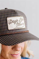 Blonde smiling woman wearing a plaid hat with a brown rope across the front, and a patch that is cream with brown embroidery that says Days Like These.