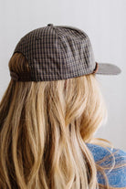 Blonde smiling woman wearing a plaid hat with a brown rope across the front, and a patch that is cream with brown embroidery that says Days Like These.