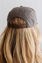 Blonde smiling woman wearing a plaid hat with a brown rope across the front, and a patch that is cream with brown embroidery that says Days Like These.