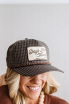 Blonde smiling woman wearing a plaid hat with a brown rope across the front, and a patch that is cream with brown embroidery that says Days Like These.