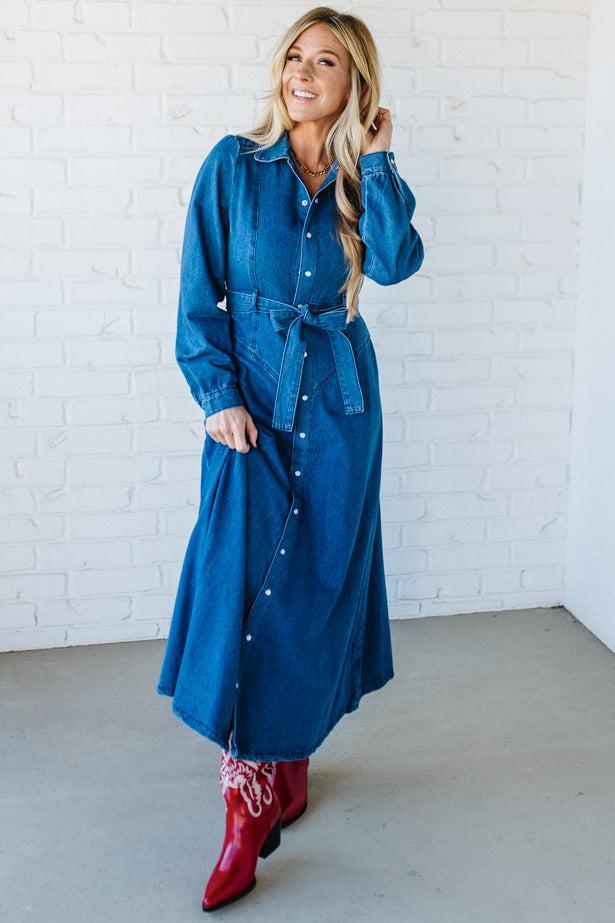 Woman wearing a blue denim dress with a white brick wall background