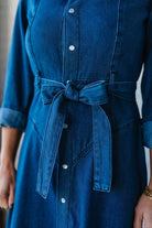 Blue denim dress with a belt on a neutral background