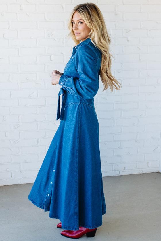 Woman wearing a blue dress with a white brick wall background