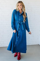 Woman wearing a blue denim dress with a white brick wall background