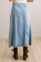 Blonde woman in a studio with light floor and a paneled wall behind, wearing a Denim Diagonal Line Detail Midi Skirt.