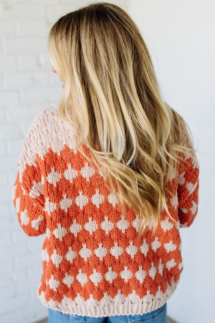 Person wearing a patterned sweater with a neutral background