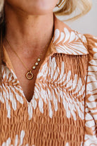 Close-up of a person wearing a patterned dress with a necklace featuring a pendant.