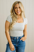 Woman wearing a striped shirt and jeans against a neutral background