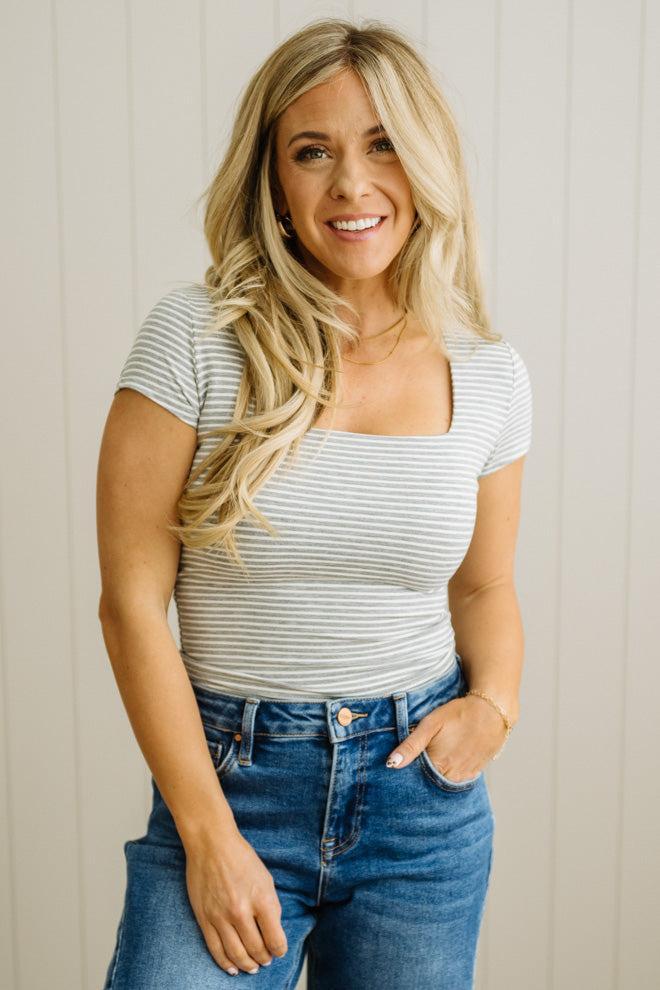 Woman wearing a striped shirt and jeans against a neutral background