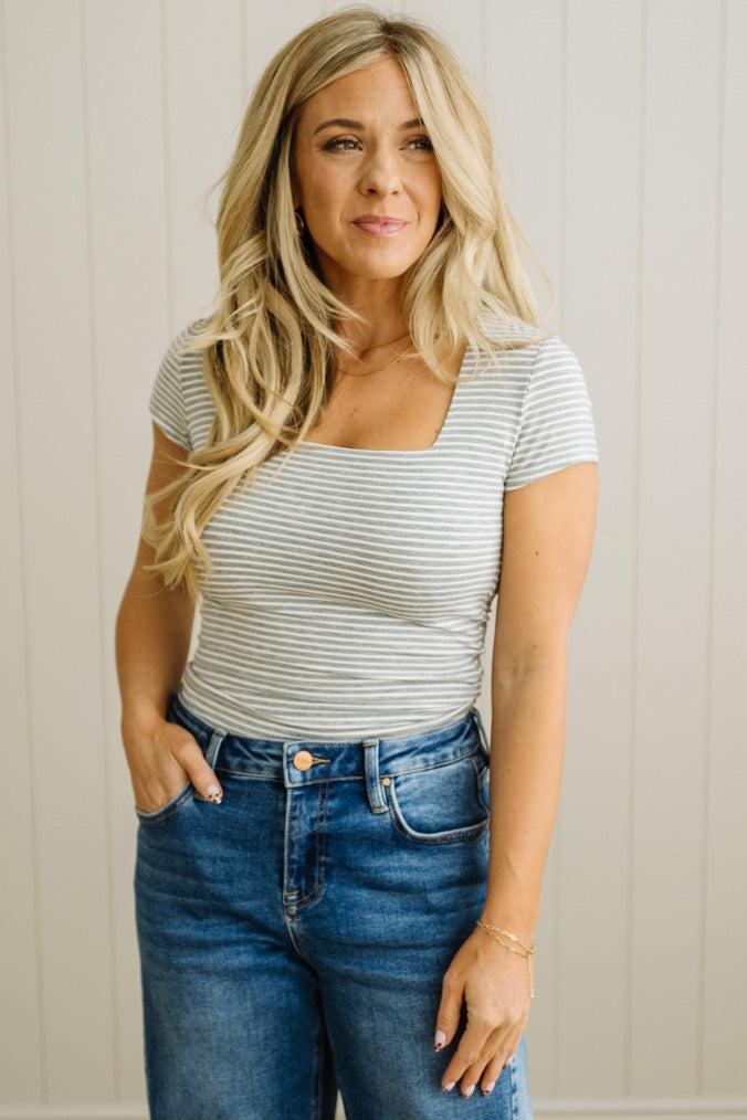 Woman wearing a striped shirt and jeans against a neutral background