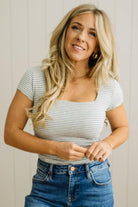 Woman wearing a striped shirt and jeans against a neutral background
