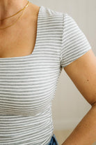 Person wearing a gray and white striped shirt with a plain background