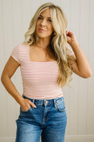 Woman wearing a striped top and jeans against a neutral background