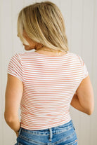 Woman wearing a striped shirt and jeans against a plain background