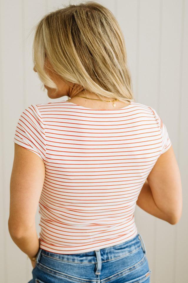 Woman wearing a striped shirt and jeans against a plain background