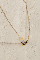 Gold necklace with a pendant on a textured beige surface