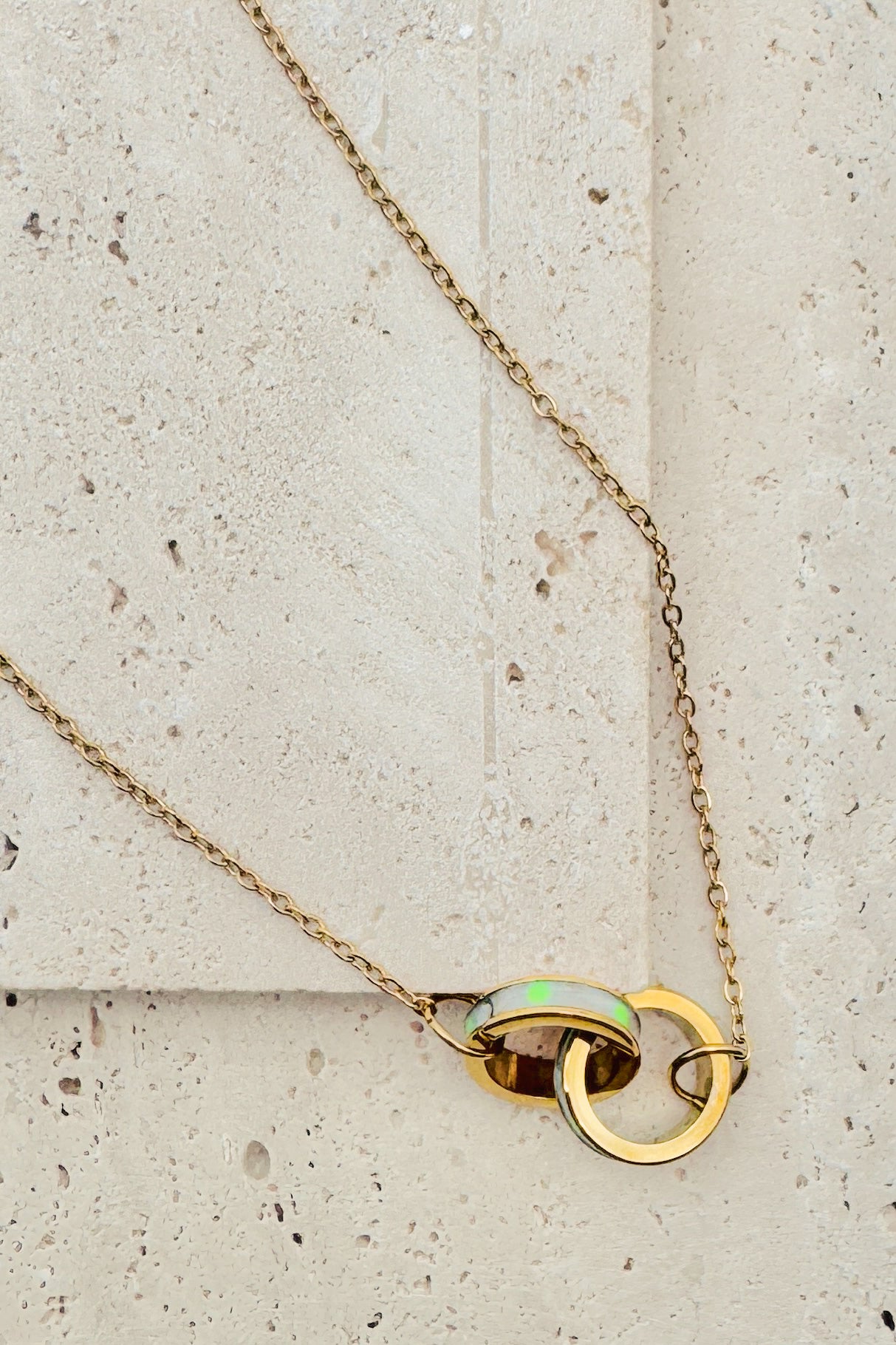 Gold necklace with a pendant on a textured beige surface