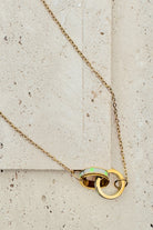 Gold necklace with a pendant on a textured beige surface