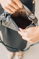 Blonde woman in a black dress with a Convertible Woven Crossbody Handbag in black vegan leather.