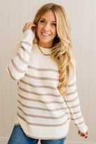 Woman wearing a cream and brown striped sweater with a neutral background