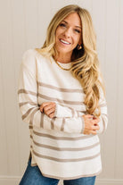 Woman wearing a white and brown striped sweater against a neutral background