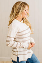 Woman wearing a striped sweater and jeans against a neutral background