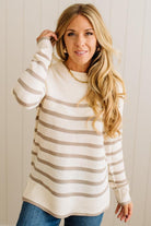 Woman wearing a cream and beige striped sweater against a plain background