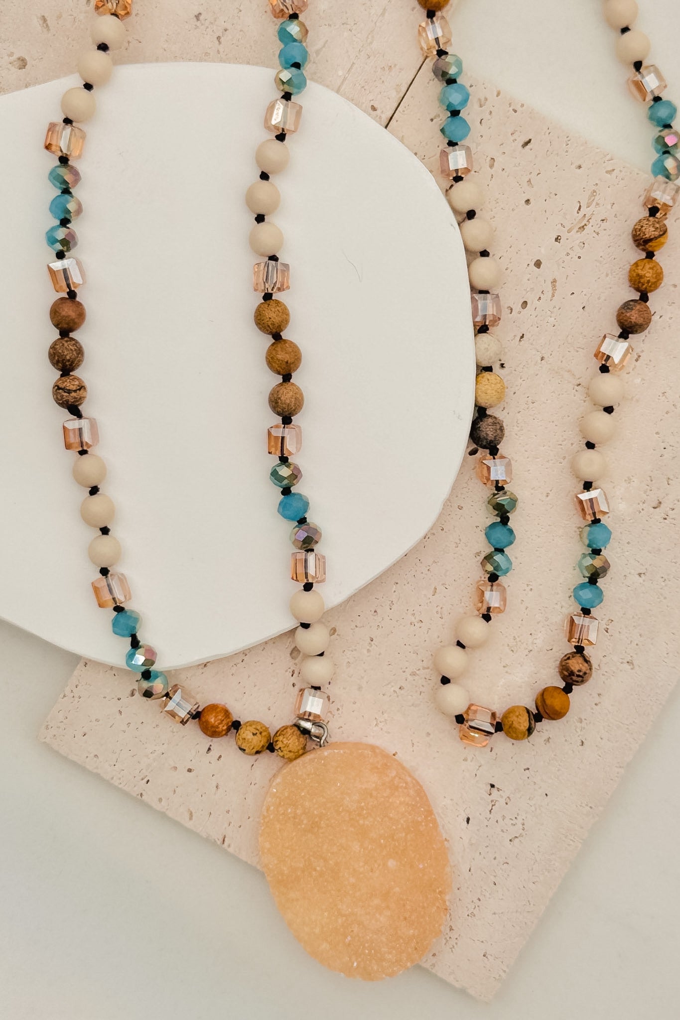 Three beaded necklaces on a textured surface with a neutral background